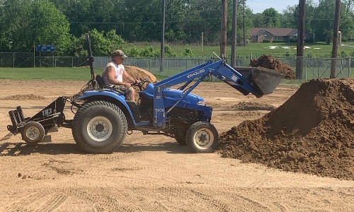 front end loader tractor spreading hoosier mix ball field dirt